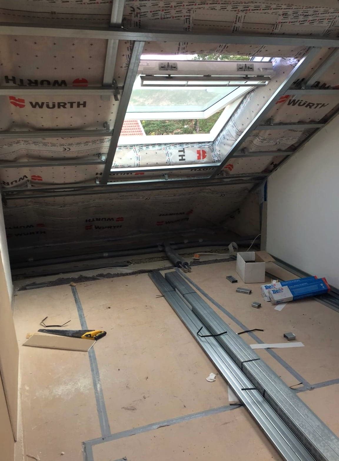 Dachgeschoss im Rohbau mit Metall-Ständerwerk unter der Dachschräge, Unterspannbahn und Dachfenster